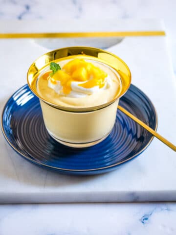 Mango Mousse served in a glass bowl on top of a blue saucer.