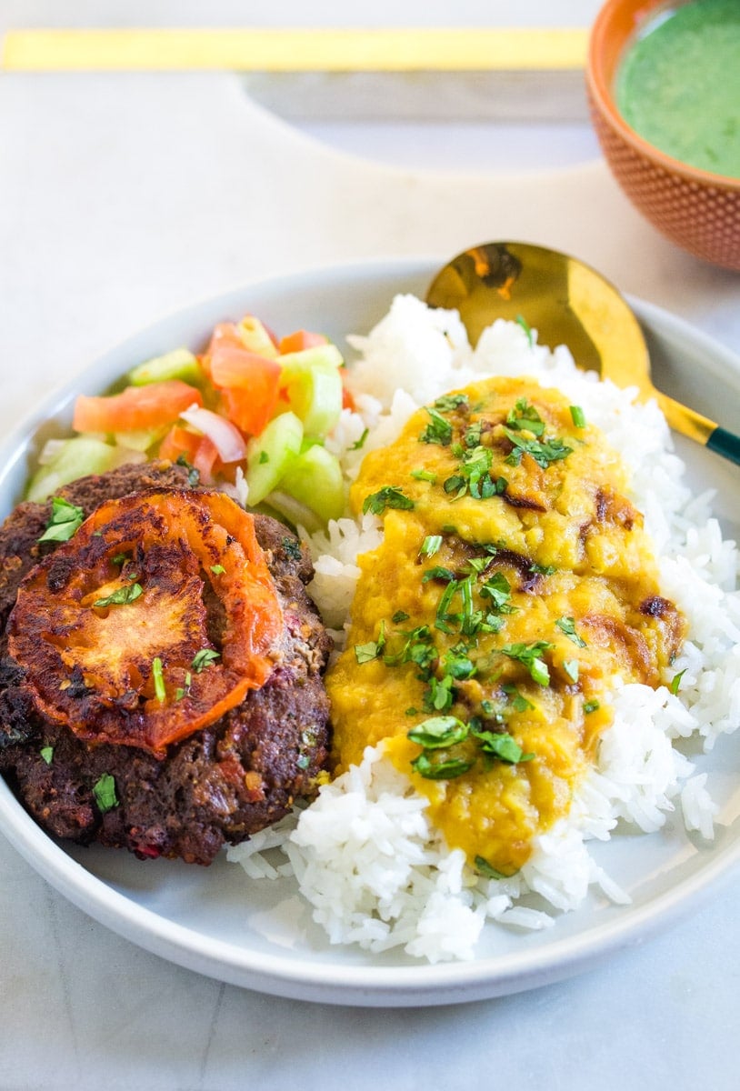 Chapli kabab served with masoor dal, kachumber salad, and mint raita.