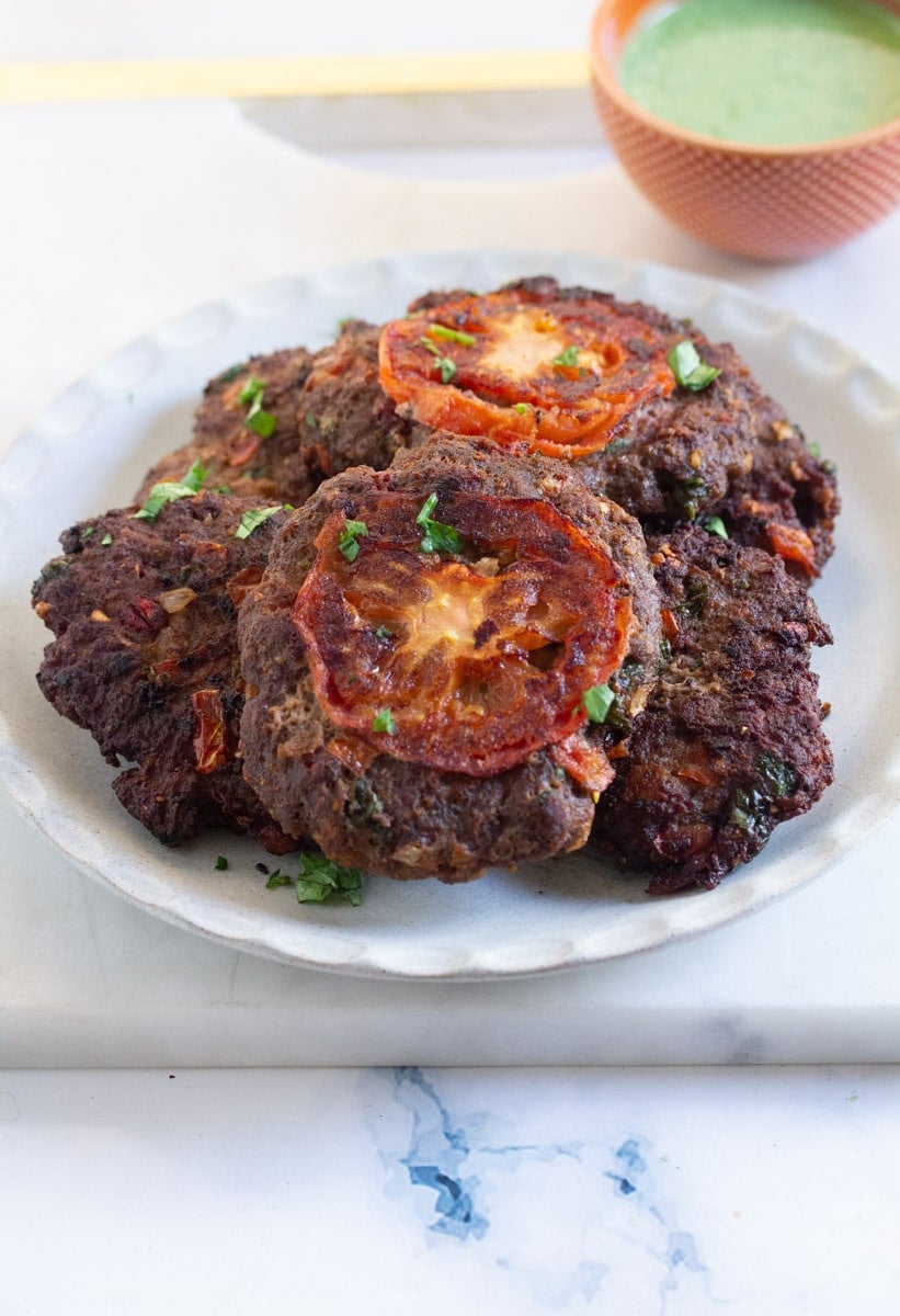 Peshawari chapli kabab served on a light grey plate.