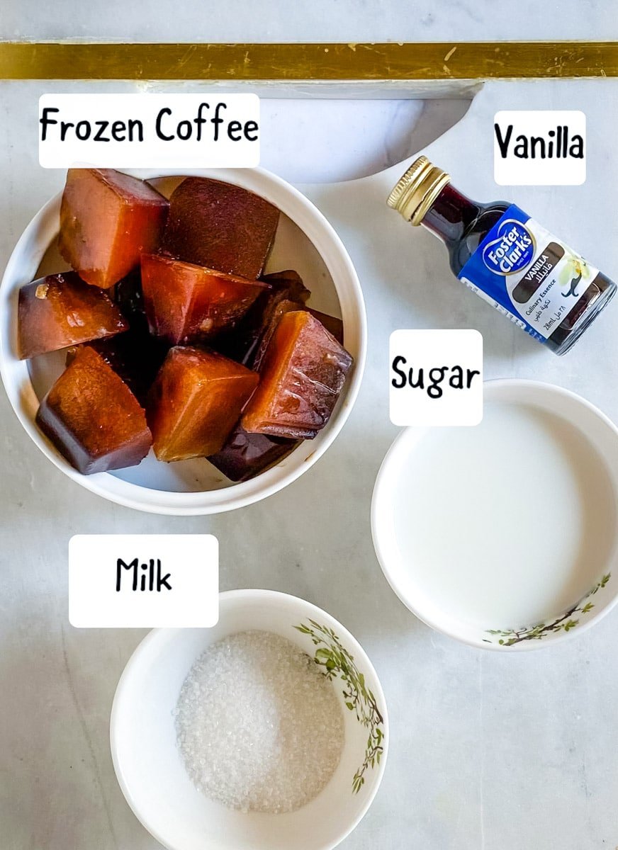 Ingredients needed for icy coffee drink laid out on a white marble slab.