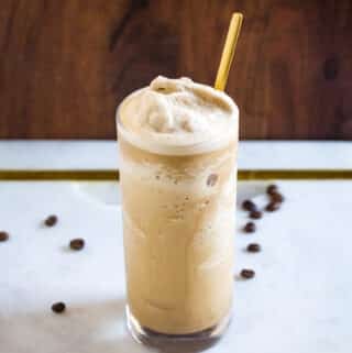 A tall glass of coffee slushie with a gold spoon inserted in the glass.