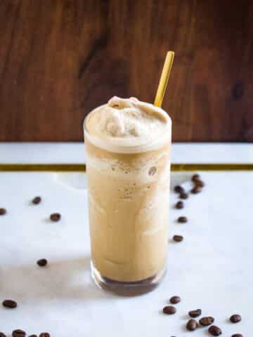 A tall glass of coffee slushie with a gold spoon inserted in the glass.