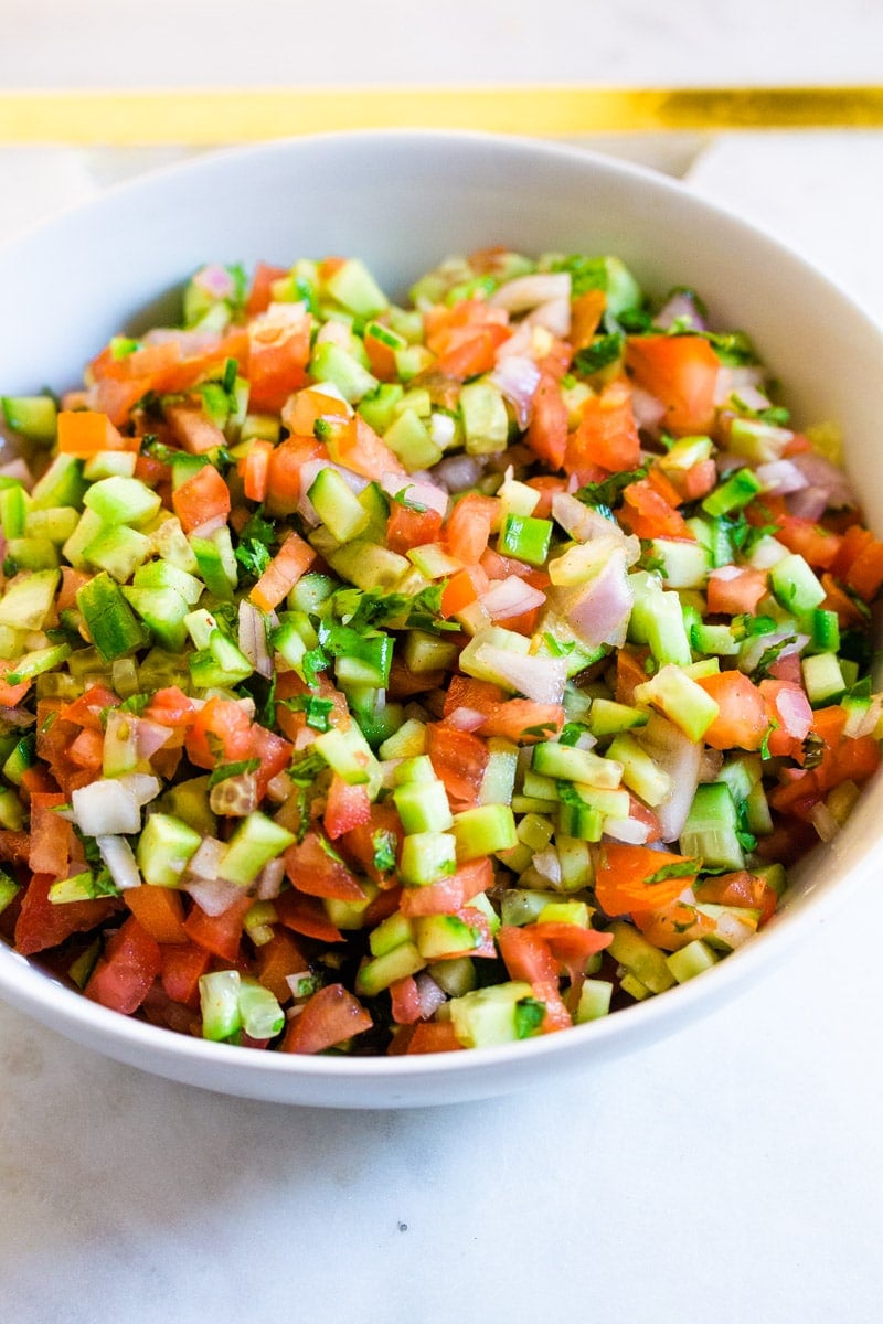 A bowl full of Indian Salad placed on a white marble slab.