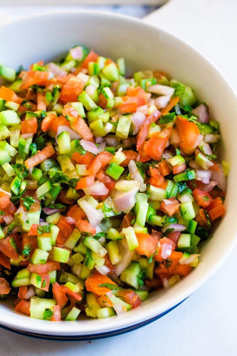 A close up shot of kachumber salad in a large white bowl.