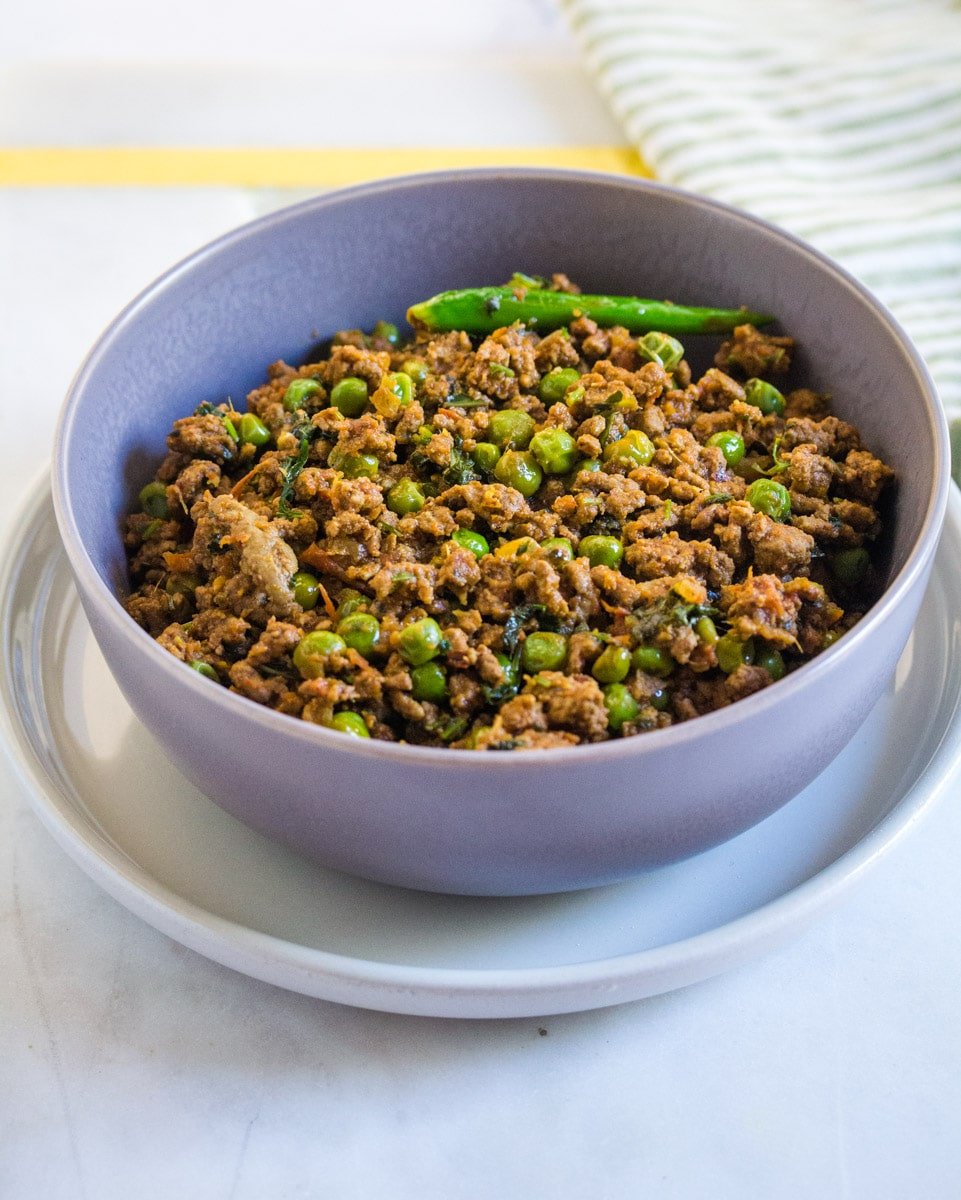 Keema Matar served in a grey bowl, topped with a green chili for garnish.