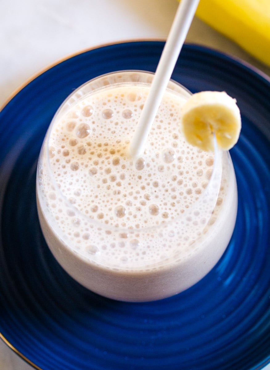 Close up shot of Korean Banana Milk in round glass garnished with a slice of banana.