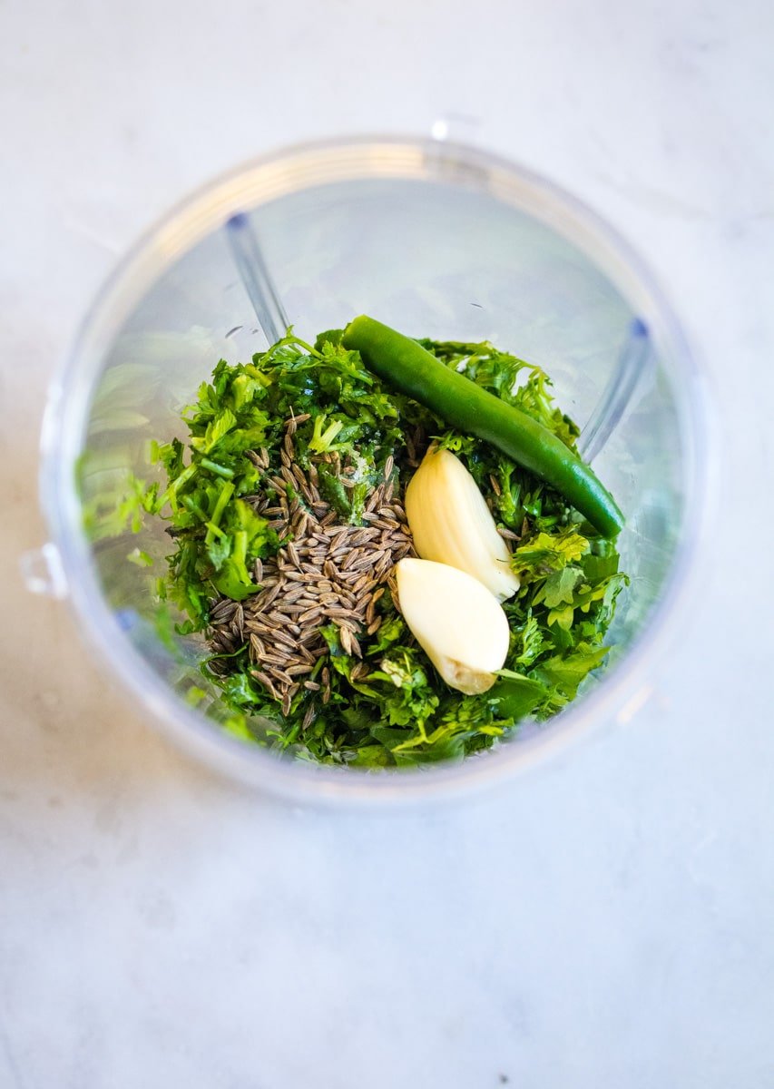 Green chili, coriander leaves, mint leaves, garlic, and cumin seeds in a blender.