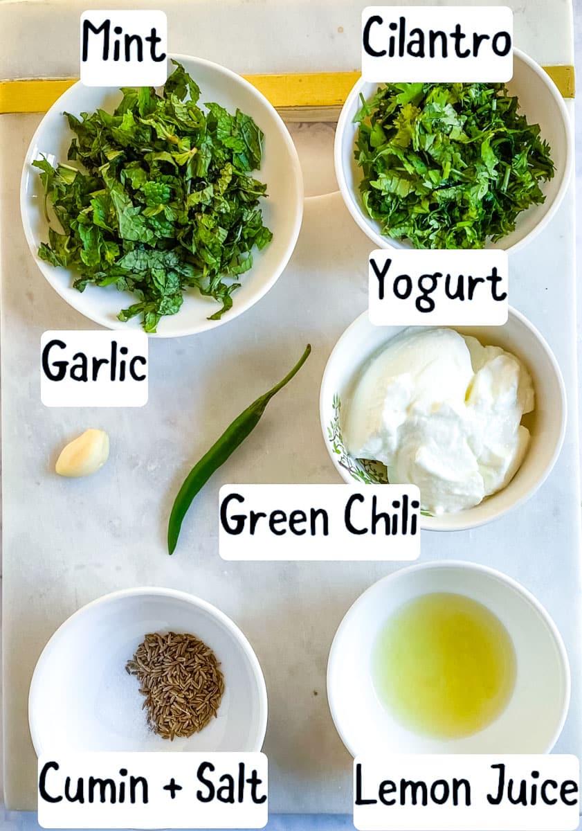 Ingredients for mint raita laid out on a white marble slab. 