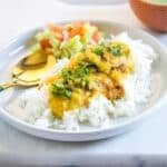 A plate of yellow daal, rice, kachumber salad and mint raita.