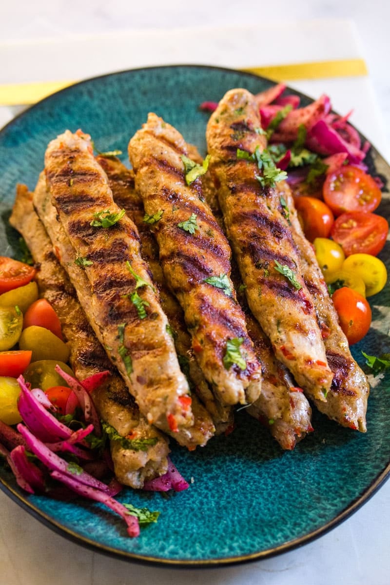 Top view of chicken adana on plate with veggies.