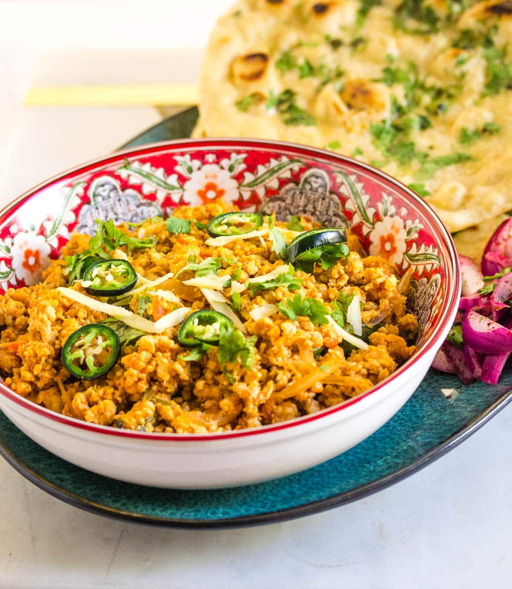 Chicken keema served with a side of naan and sliced red onion. 