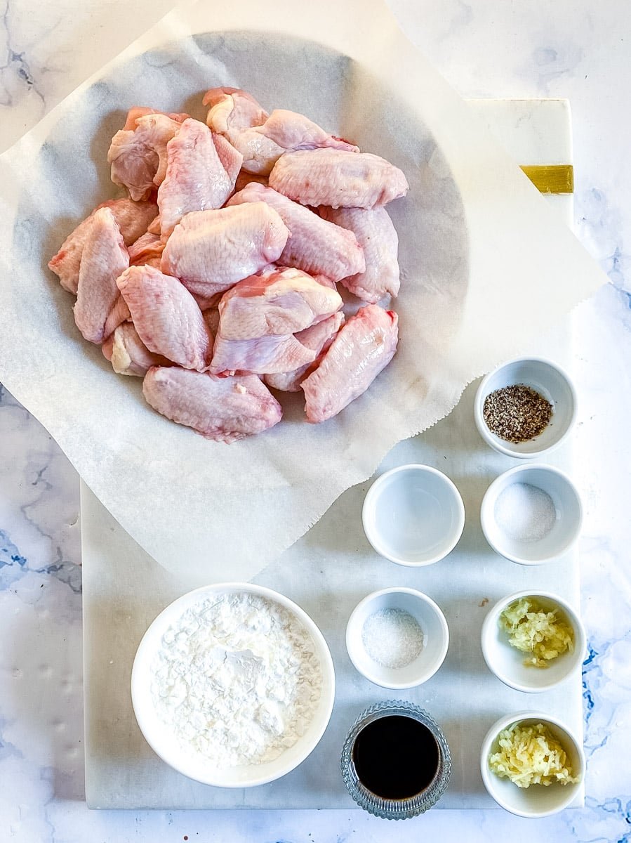 Ingredients needed to make Chinese chicken wings laid out on a white marble slab.