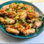 A platter of salt and pepper chicken wings topped with fried chilies and garlic.