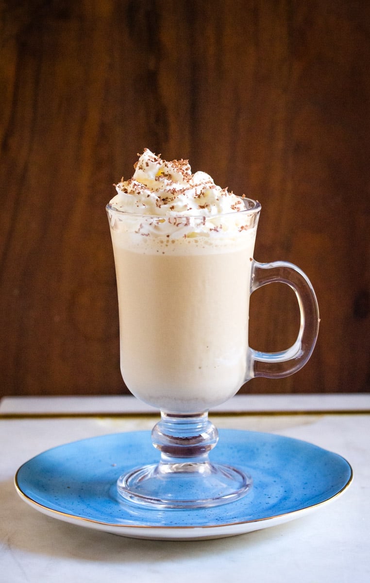 A vertical shot of coffee milkshake topped with whipped cream and chocolate shavings.