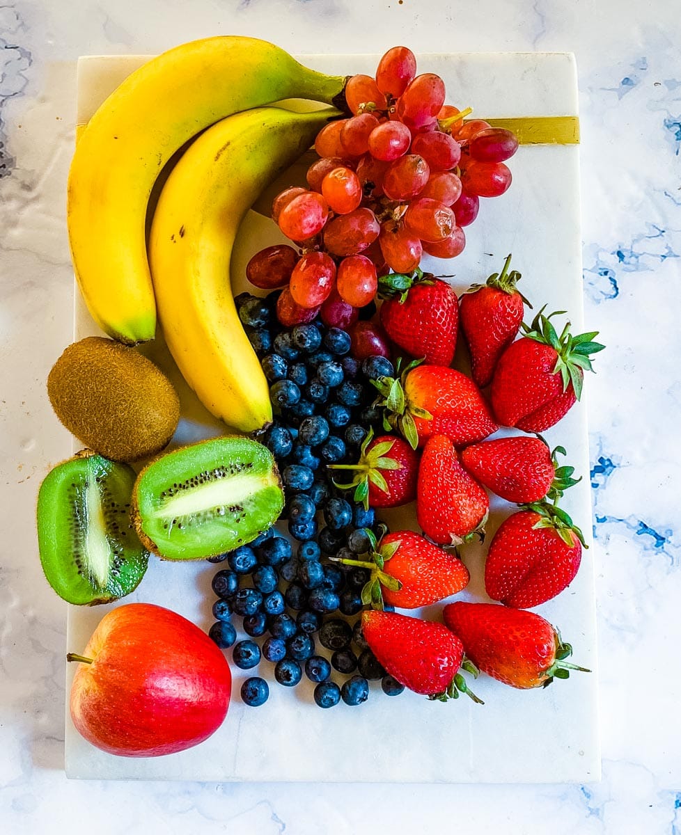 An overhead shot of assorted fruit placed on a white marble slab.