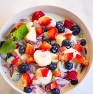 Overhead shot of creamy fruit salad in a light grey bowl.