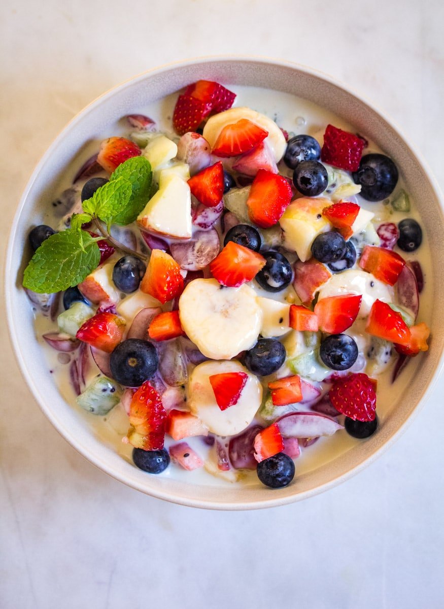 Overhead shot of creamy fruit salad in a light grey bowl.