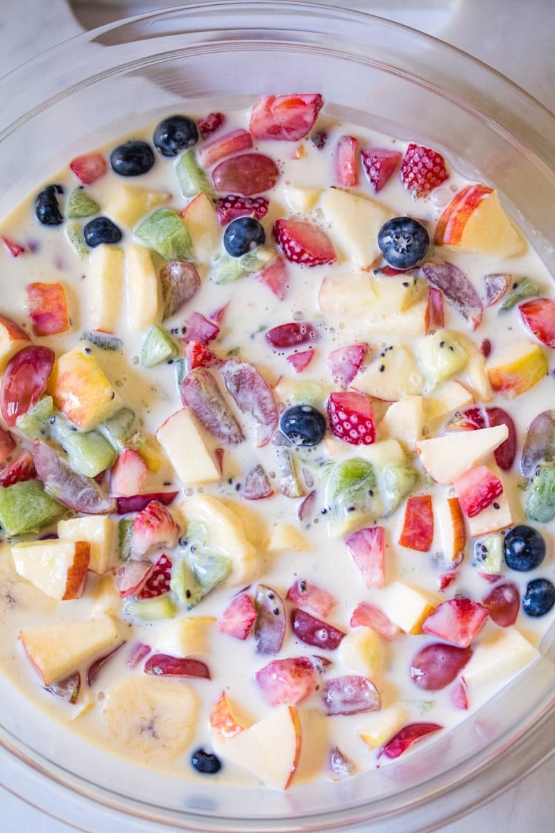 Overhead shot of chopped fruit mixed in a creamy condensed milk dressing.