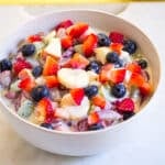 A bowl of creamy fruit salad mixed with a sweetened condensed milk dressing.