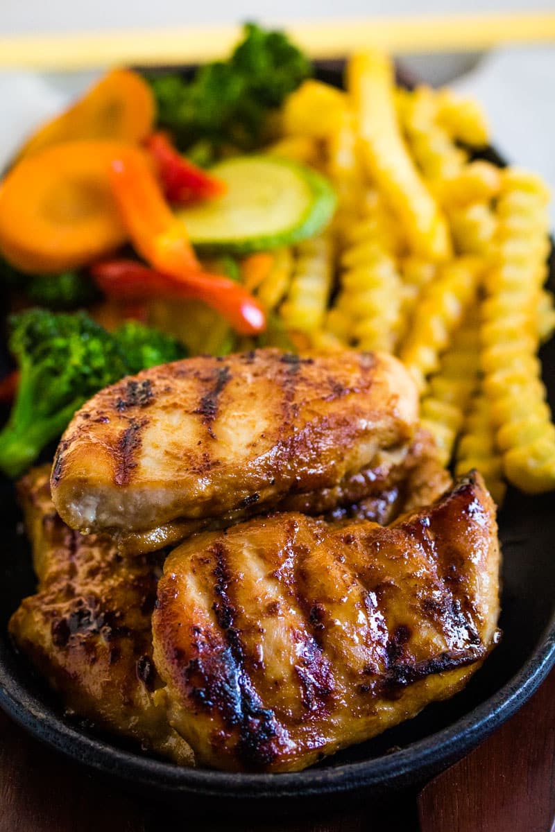 Grilled chicken steak served with sauteed vegetables and french fries