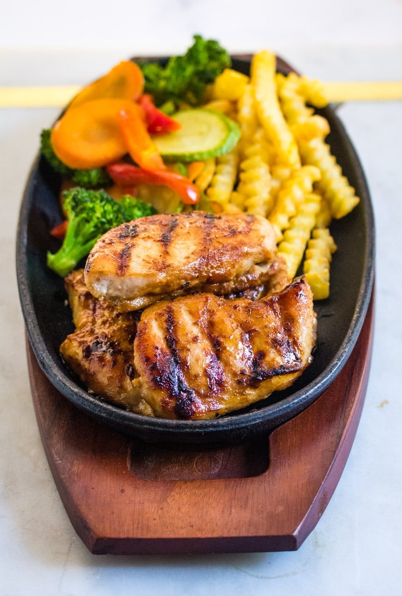 Grilled chicken steak served with sauteed vegetables and french fries
