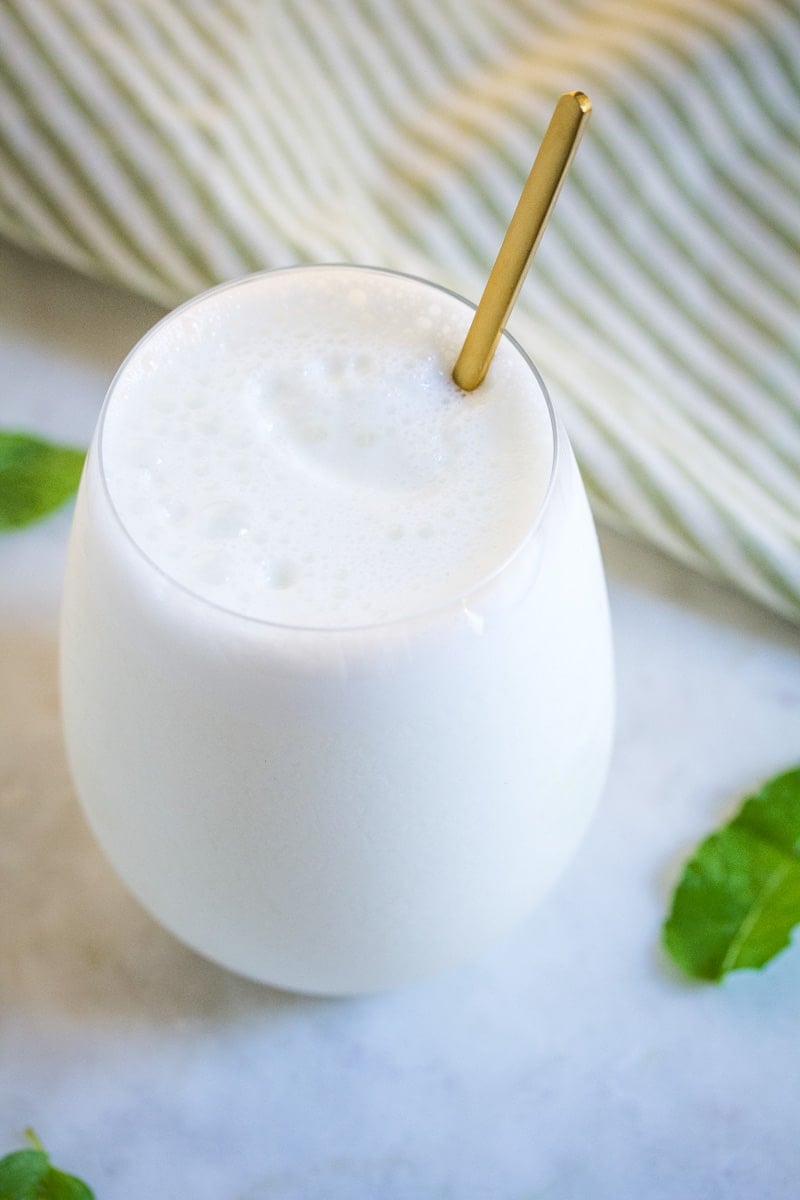 A creamy yogurt drink served in a glass goblet with a golden spoon.