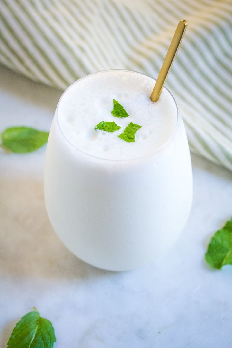 Namkeen lassi served in a round glass, and topped with fresh mint leaves.