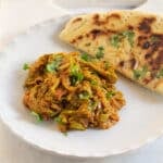 Zucchini (Torai) Curry served on a white plate with a side of naan.